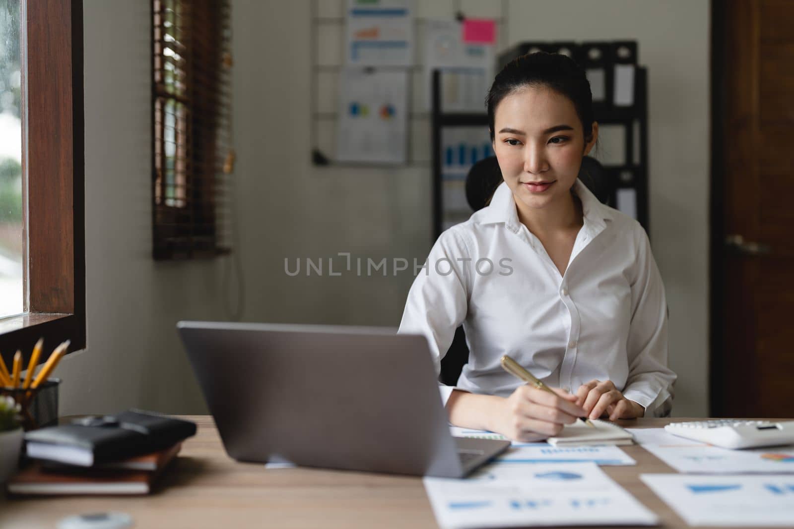 Woman accountant using calculator and laptop computer in office, finance and accounting concept.