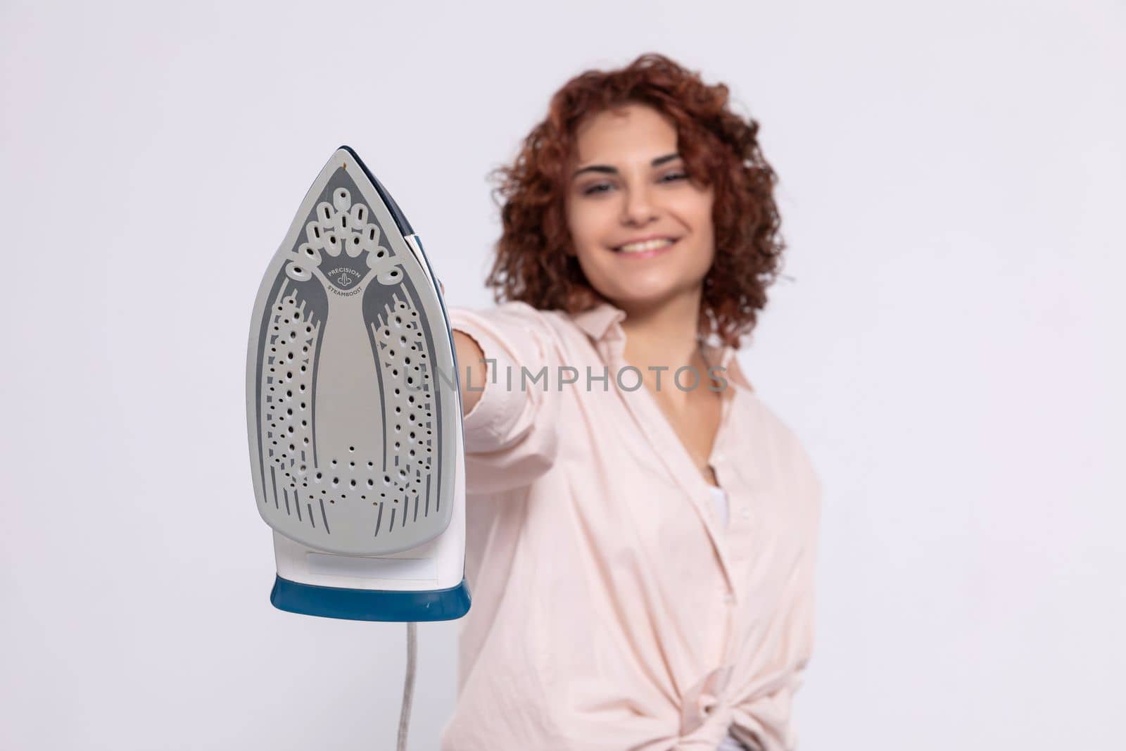 A girl with short and curly hair. An adult coquette holds an iron in her hand. Total readiness to iron clothes.