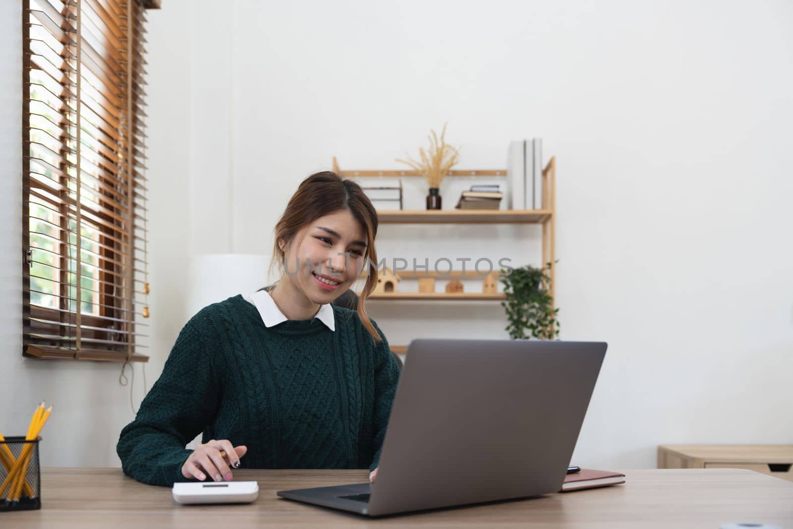 Asian woman accountant using calculator and laptop computer in office, businesswoman working at home, finance and accounting concept