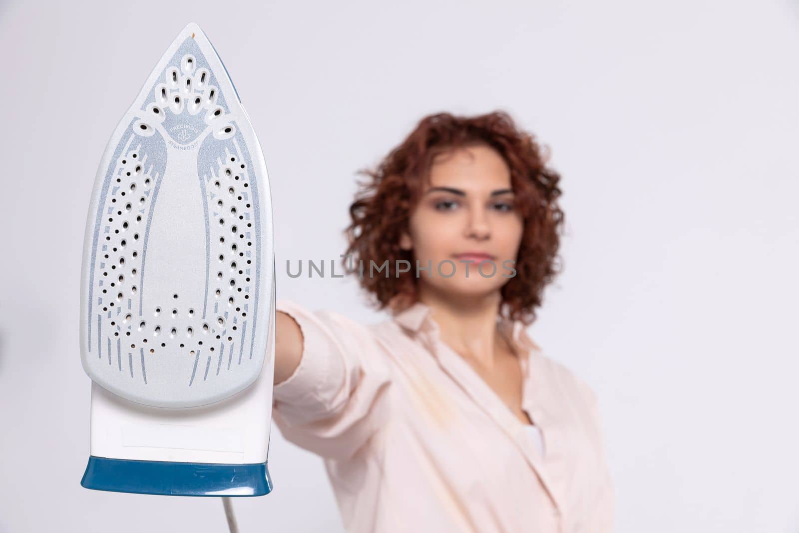 A girl with short and curly hair. An adult coquette holds an iron in her hand. Total readiness to iron clothes.