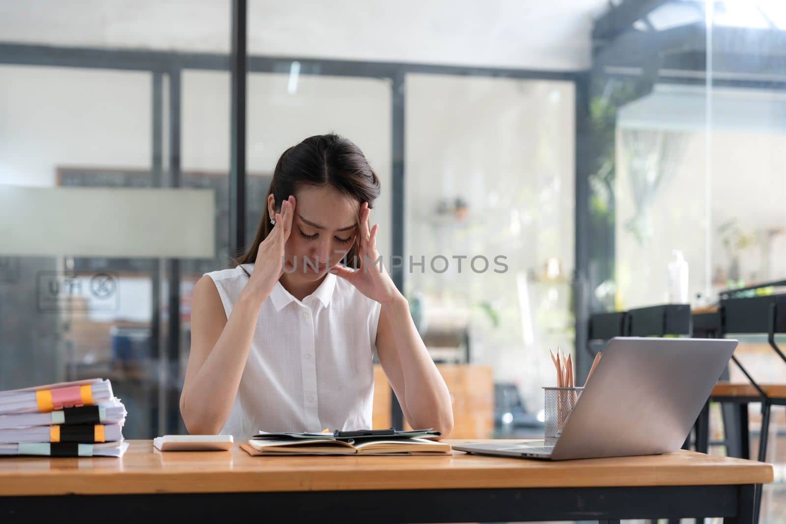 Young Business Asian women are stressed while working on laptop, Tired asian businesswoman with headache at office, feeling sick at work copy space in workplace an home office. by wichayada