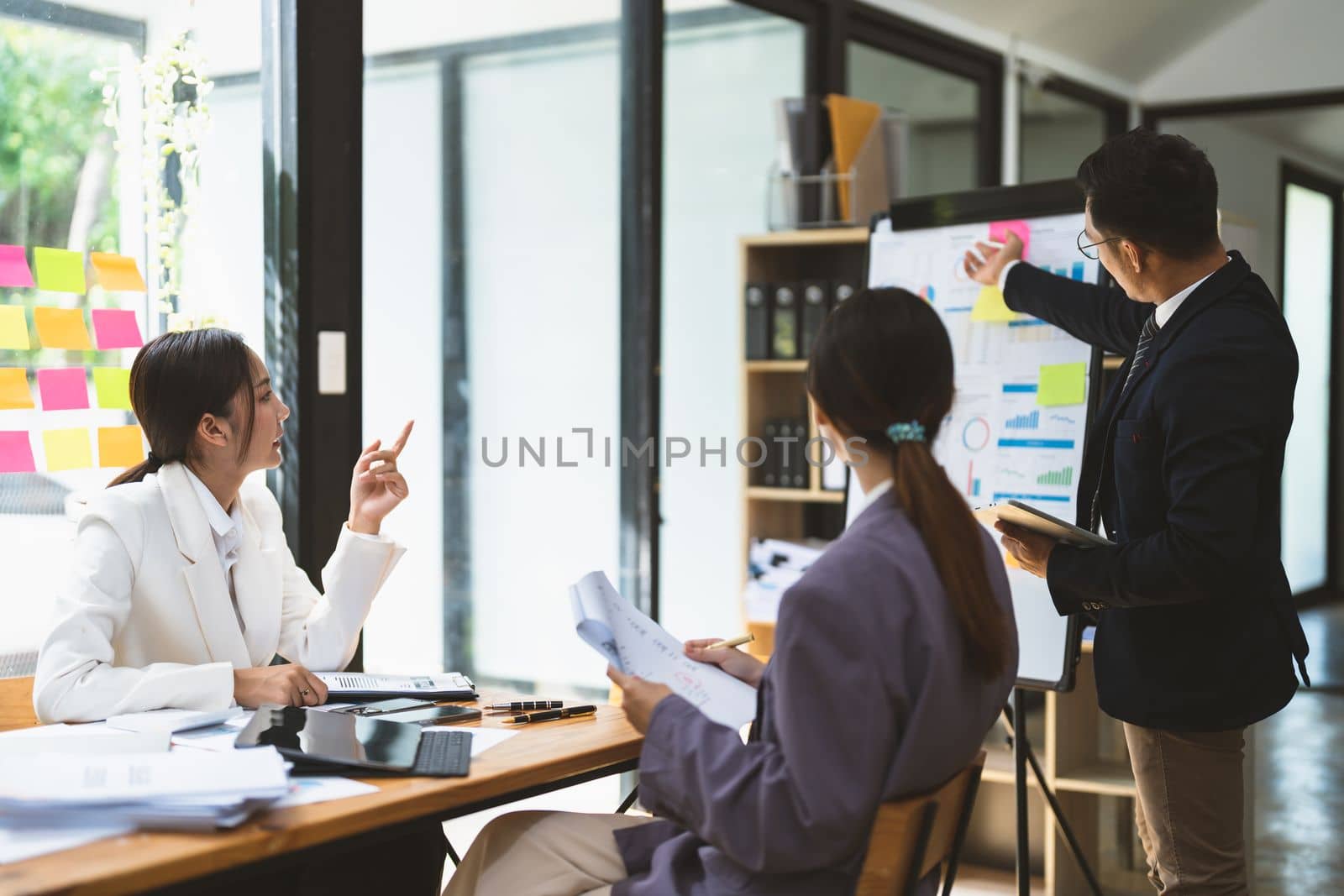 Business adviser explaining business plan strategy on flipchart to colleagues, male coach or adviser giving presentation at briefing, reporting about results or growing sales.