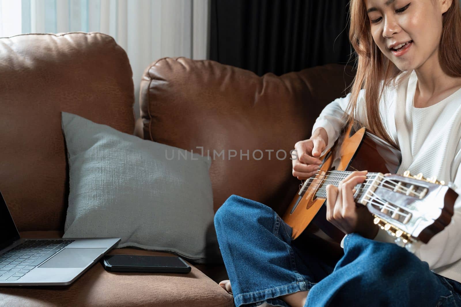 Image of happy beautiful woman playing guitar and composing song.