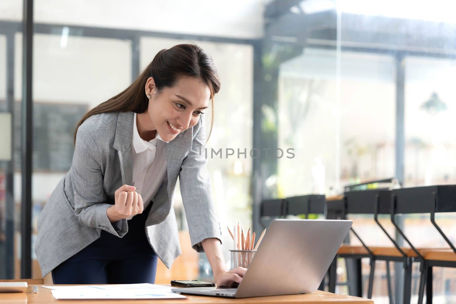 Excited happy Asian woman looking at the phone screen, celebrating an online win, overjoyed young asian female screaming with joy, isolated over a white blur background.