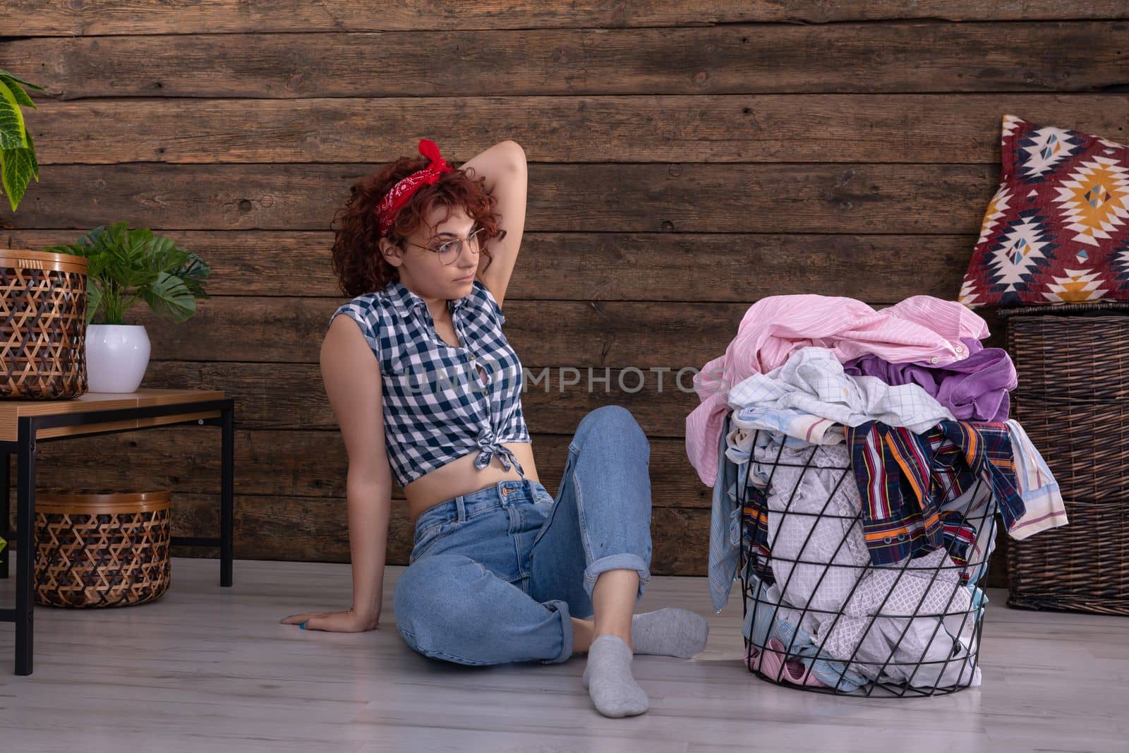 Short curly dark-colored hair. The surprised girl sees on the floor and is surprised by the large amount of wet laundry to be hung up.