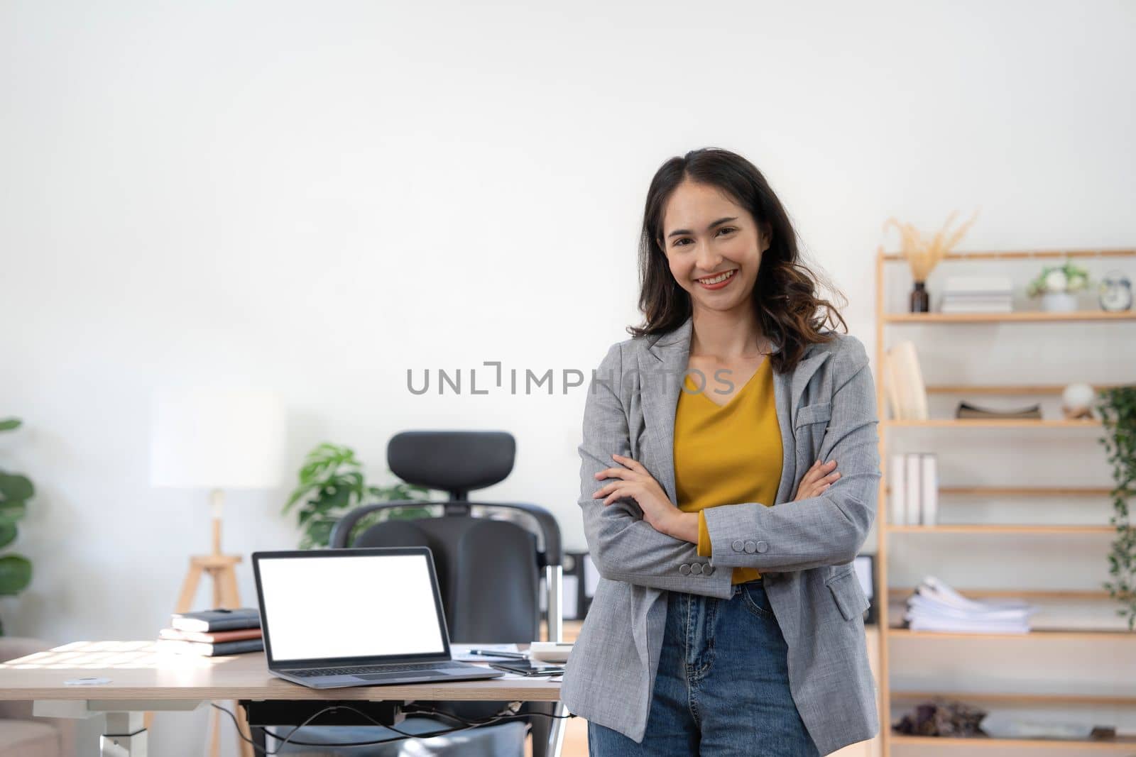 Smiling Asian beautiful female professional manager standing with arms crossed looking at camera