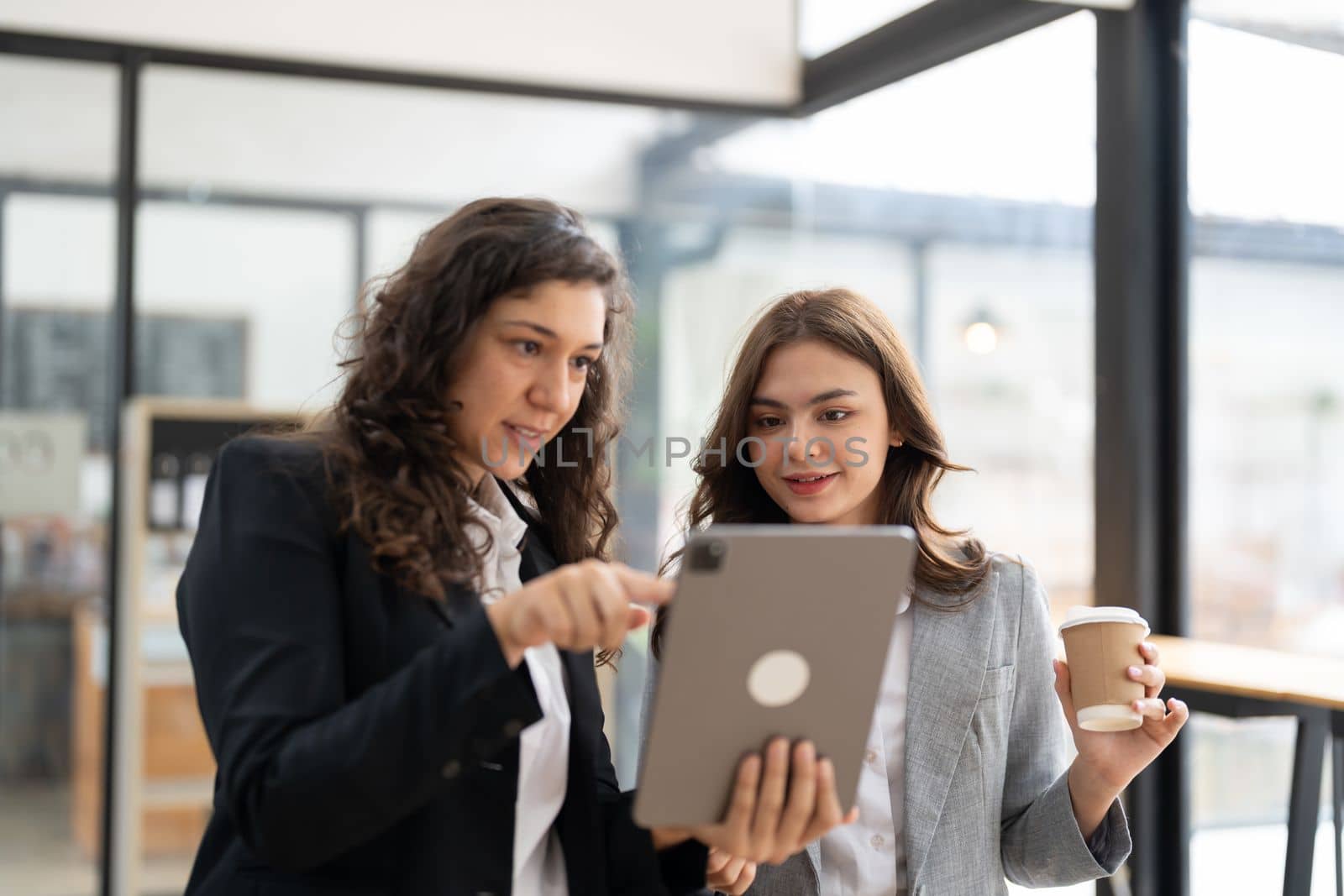 Diverse businesspeople cooperate work together discussing company financial statistics, multiracial colleagues collaborate brainstorm with finance on tablet