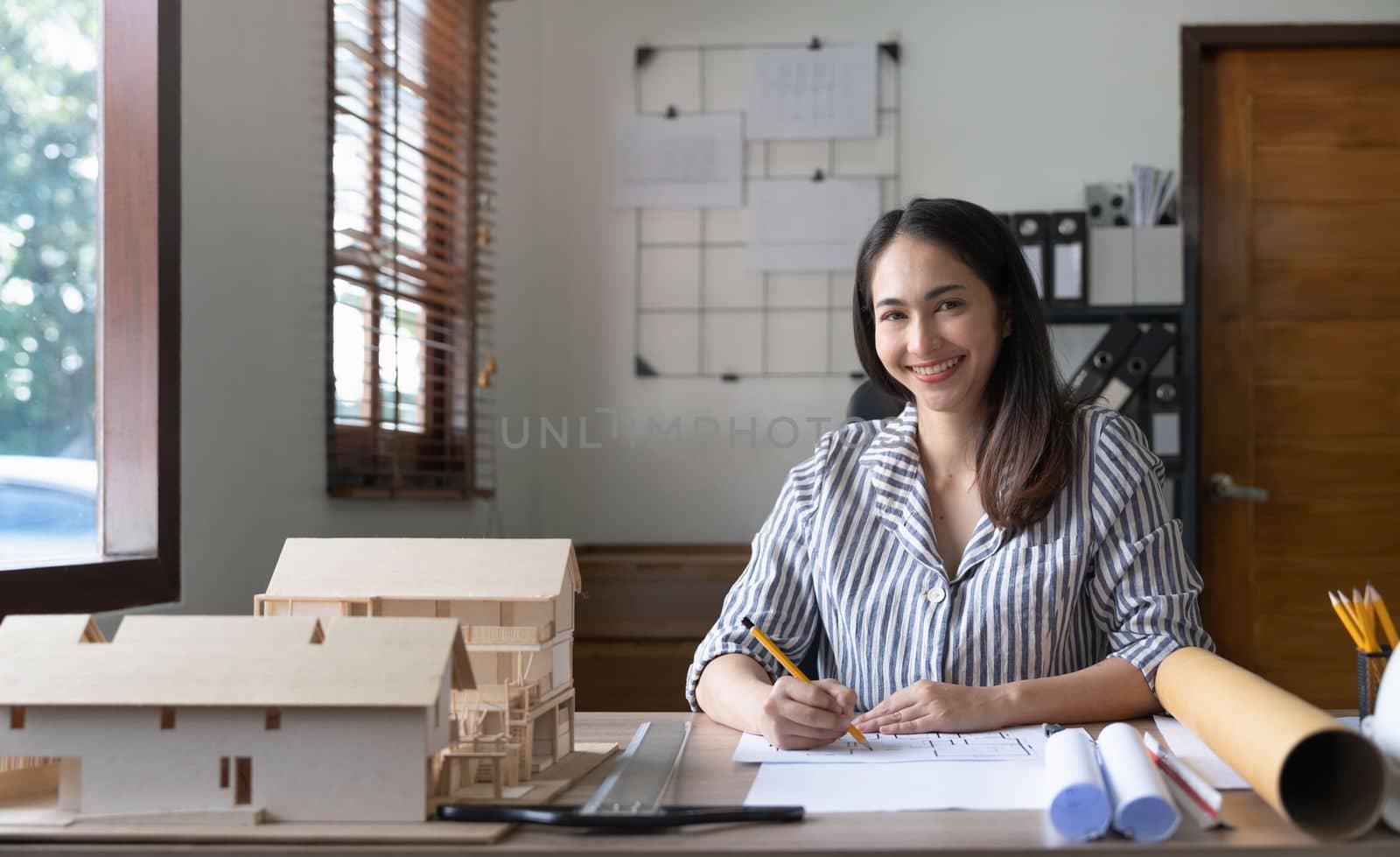 Female asian architect working on blueprint at office