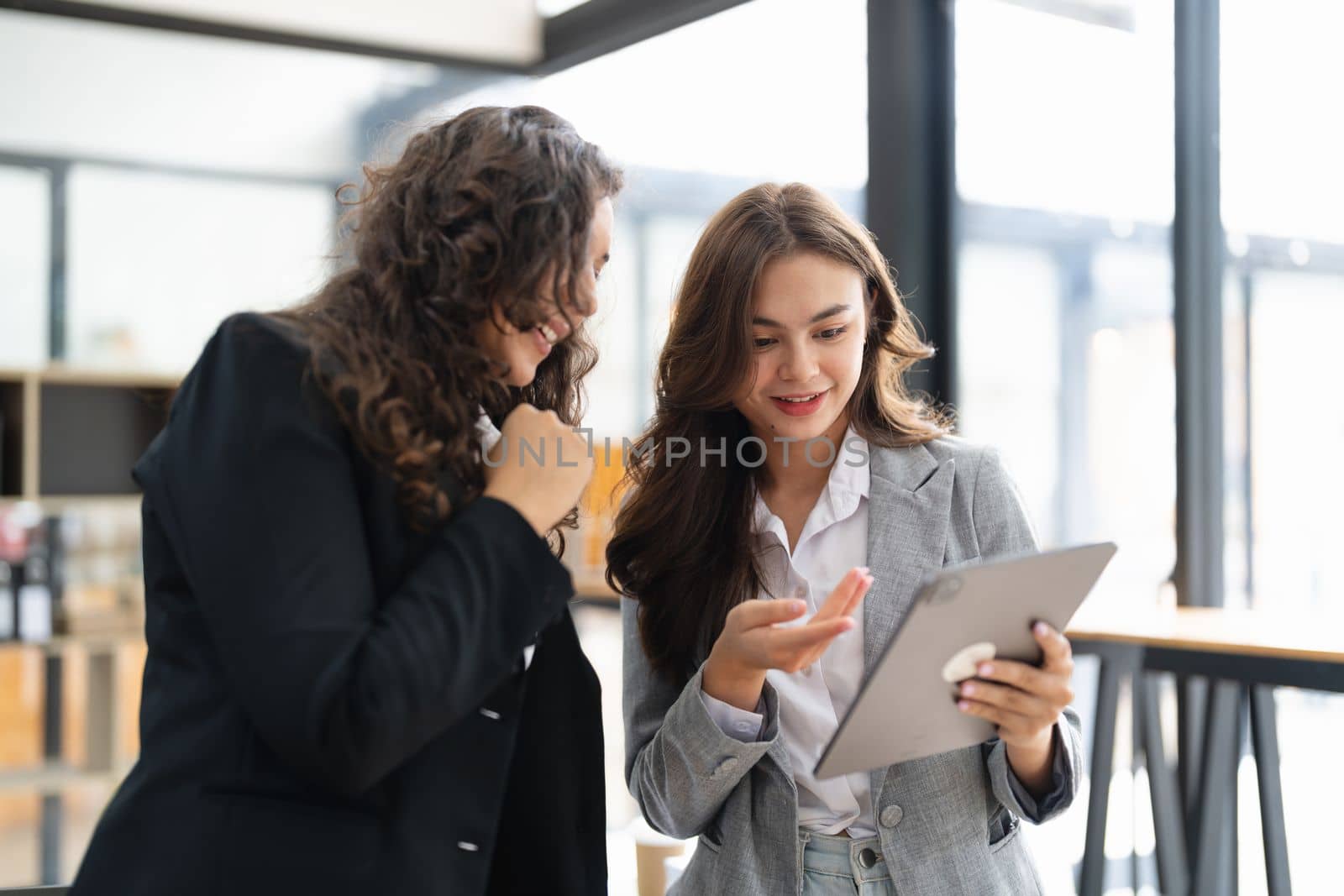 Diverse businesspeople cooperate work together discussing company financial statistics, multiracial colleagues collaborate brainstorm with finance on tablet
