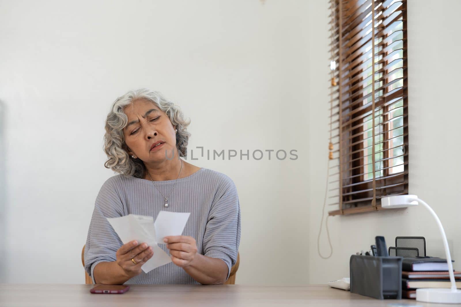 Worried Senior woman having problem about Financial economic crisis. Stressed Asian Elderly male calculate family budget, Debts, monthly expenses with calculator and laptop computer at home by wichayada