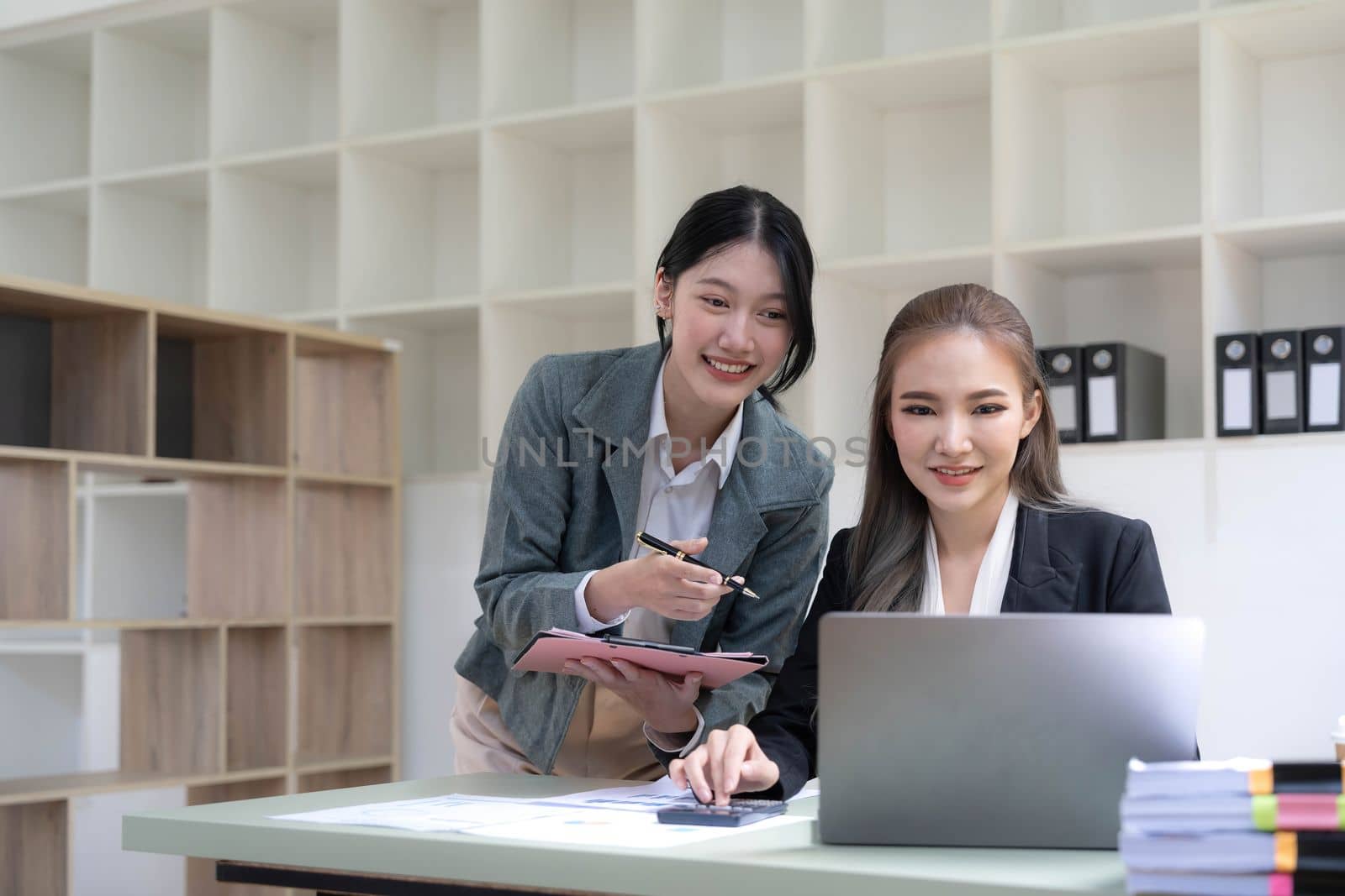 Two young Asian business woman talk, consult, discuss working with new startup project idea presentation analyze plan marketing and investment in the office. by wichayada