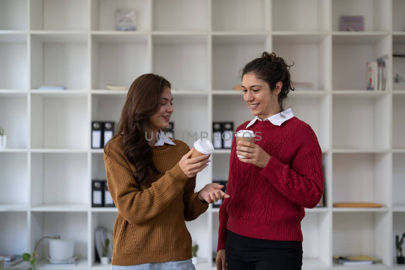 Diverse friendly coworkers coffee break talking office. Caucasian manager having discussion with asian employee meeting in office lobby discussing project, teaching new employee sharing ideas