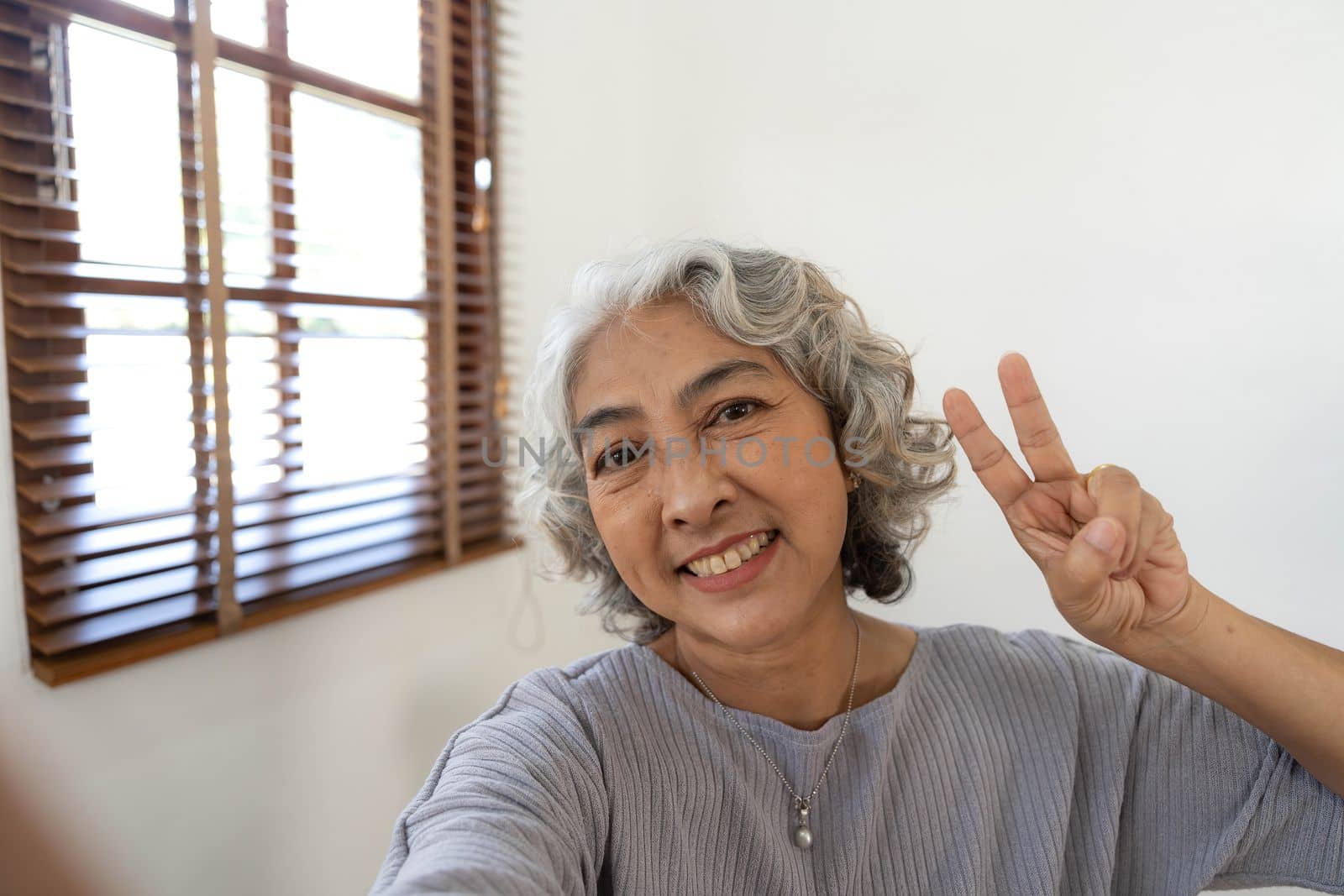 Happy Asian Elderly taking selfie photos with smartphone together in house. Portrait Senior people smiling and looking at camera. by wichayada