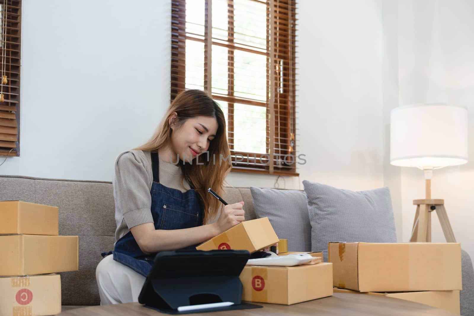 Asian woman freelancer sme business online shopping working with parcel box at home - SME business online and delivery concept.