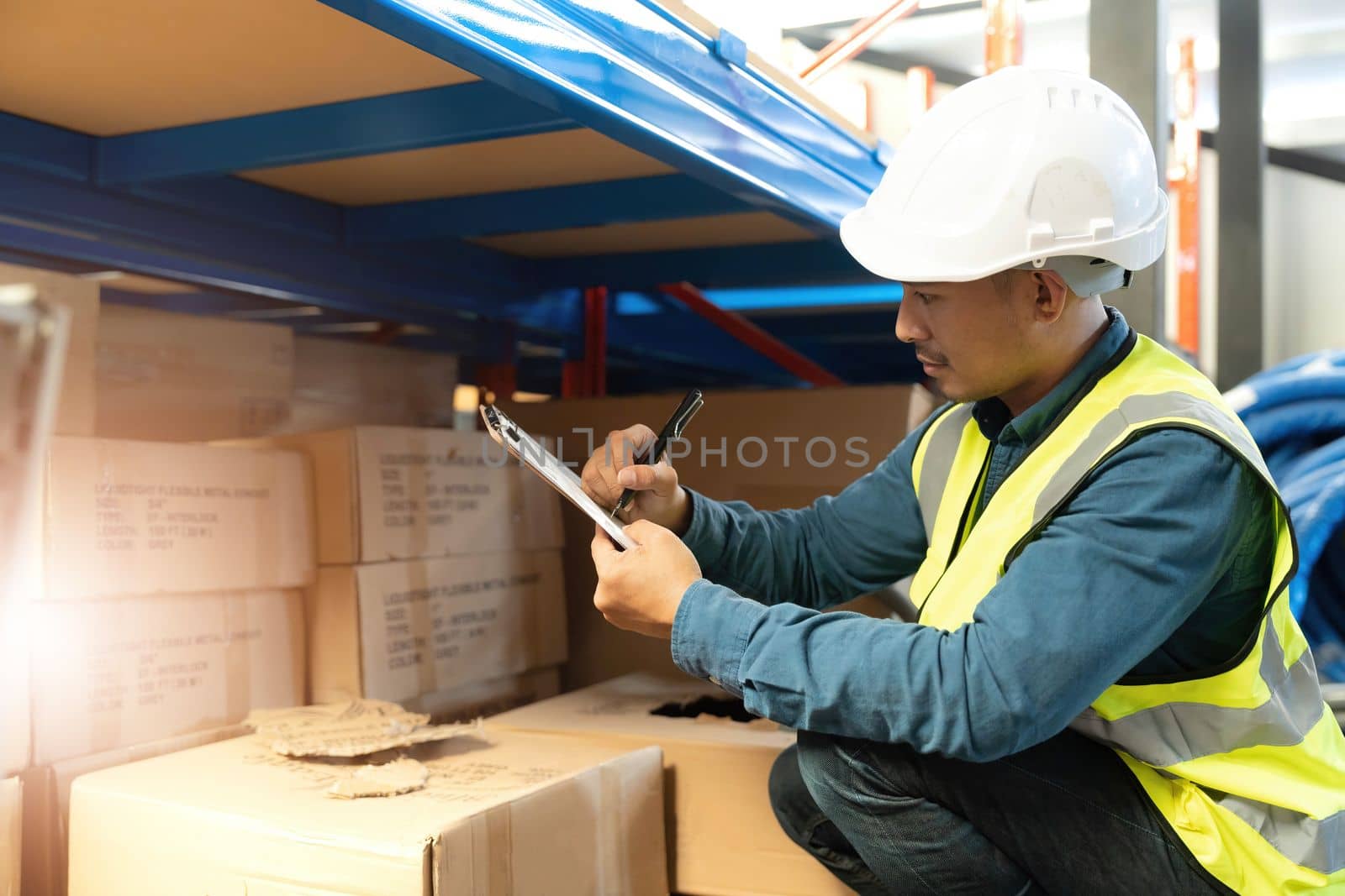 Portrait An Asian warehouse worker in a blue security suit holding clipboard working at store industry. Logistic import export concept Distribution Center. Logistics and export of business