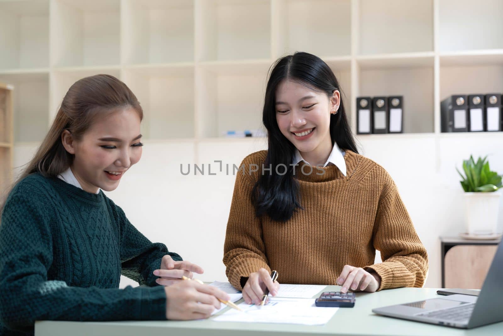 Two young Asian business woman talk, consult, discuss working with new startup project idea presentation analyze plan marketing and investment in the office. by wichayada