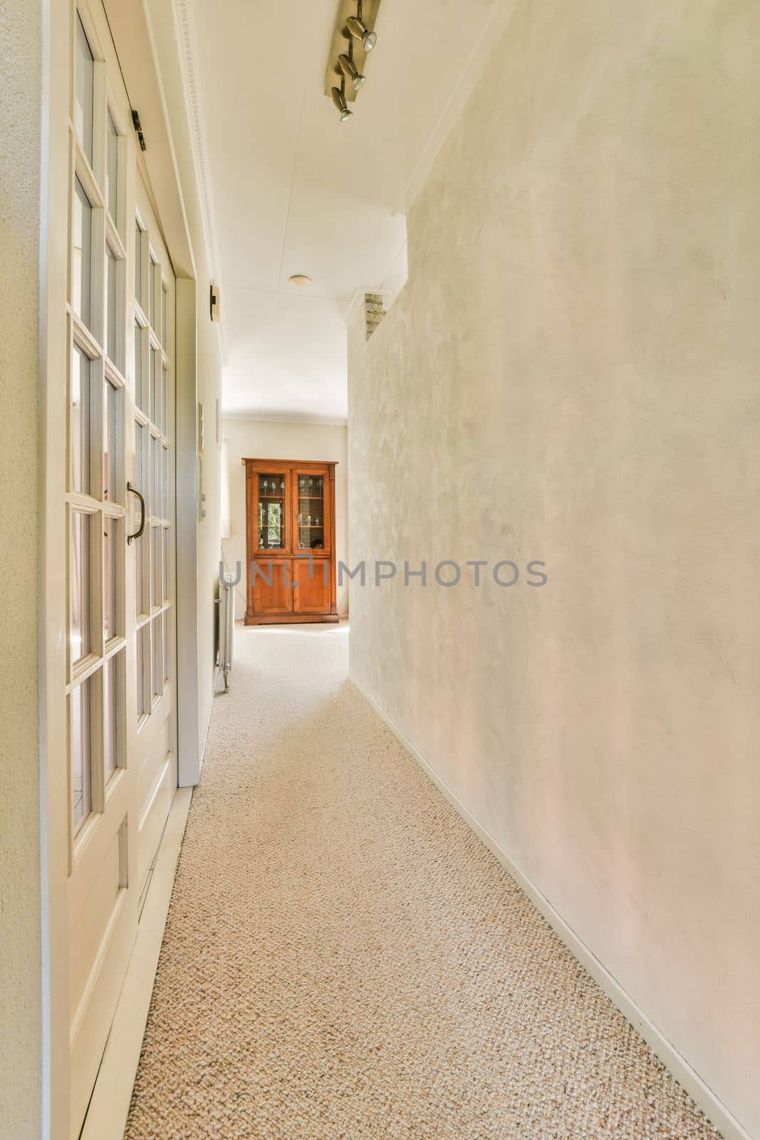 Light narrow hallway with many doors in white walls and glowing lamp over lumber floor