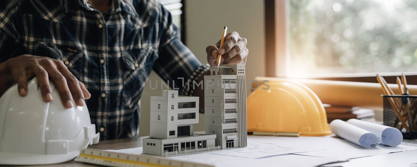 Image of engineer drawing a blue print design building or house, An engineer workplace with blueprints, pencil, protractor and safety helmet, Industry concept by wichayada