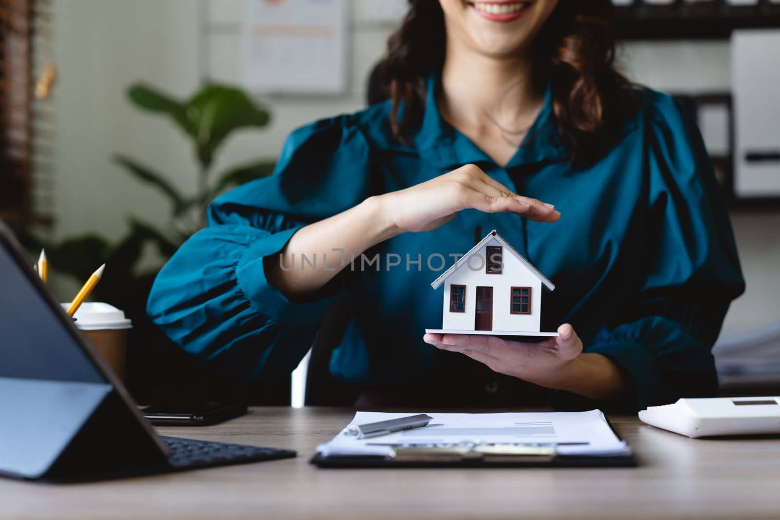 Businesswoman use their hands to protect the red roofs, the concept of protecting houses using the gestures and symbols of real estate investors, taking care of credit and contracts. by nateemee