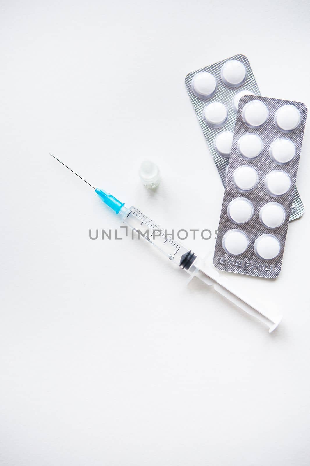 Preparation for vaccination against covid-19. Syringe, vaccine, pills, medical mask on a white table