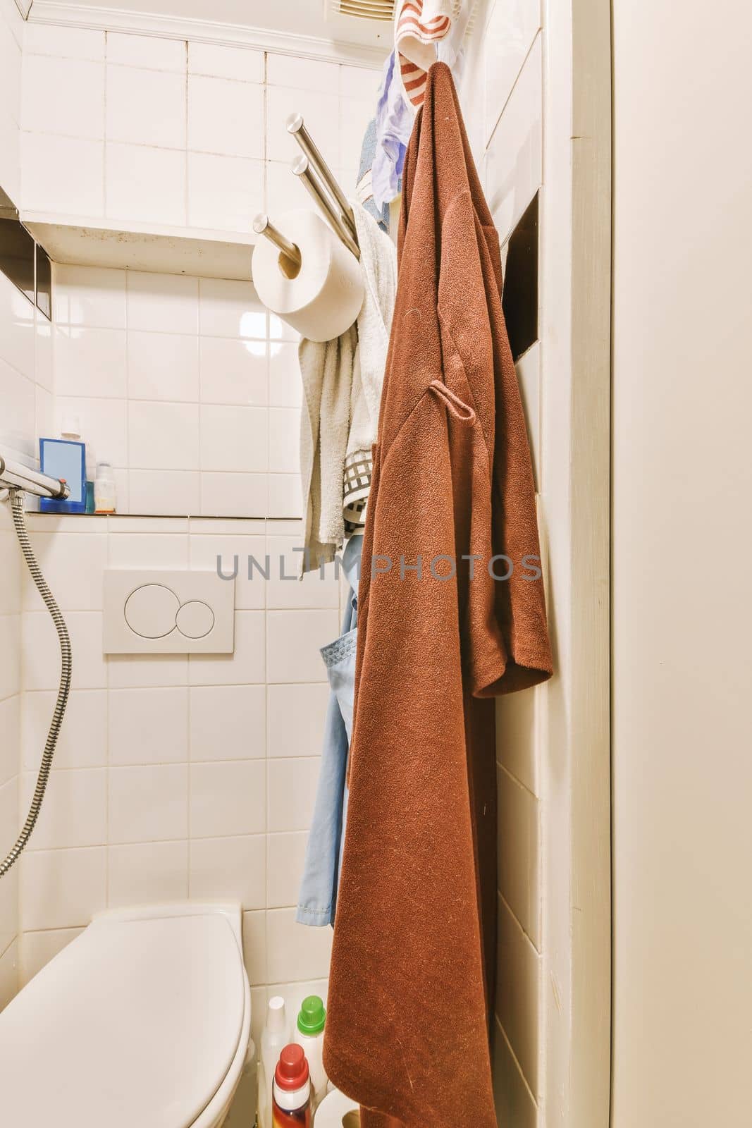 a bathroom with a towel hanging on the wall next to a toilet and a roll of toilet paper in it