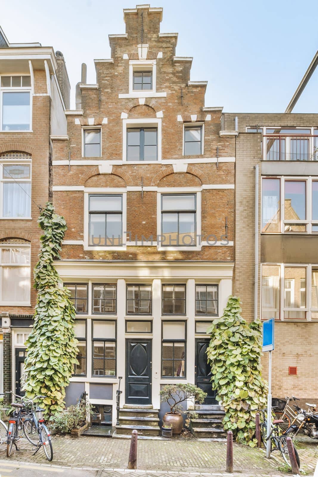 an apartment building with bicycles parked on the sidewalk next to it and two people walking by in front of them