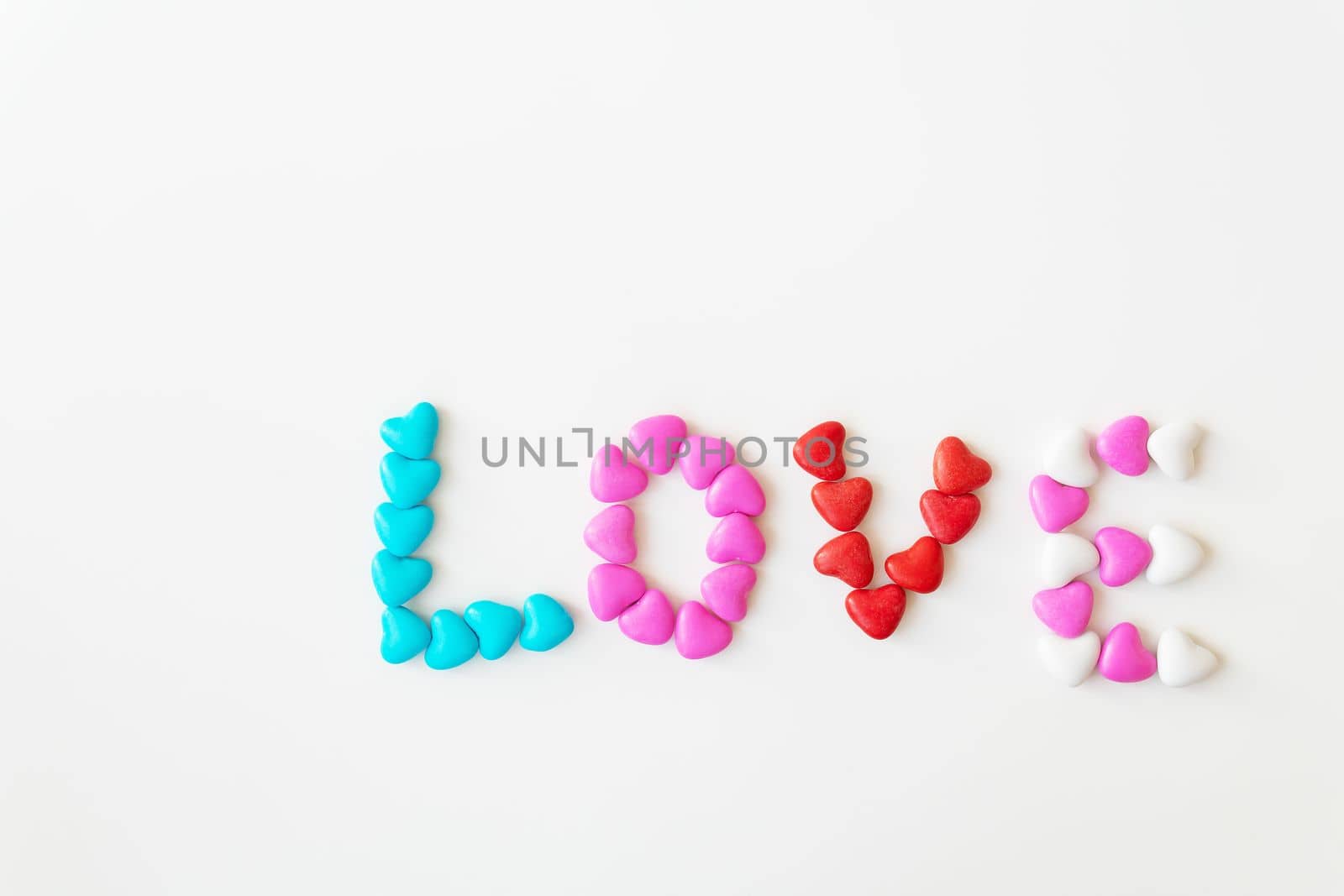 Valentine's day pattern background flat lay top view of bright candies in the shape of the word love scattered on a white background