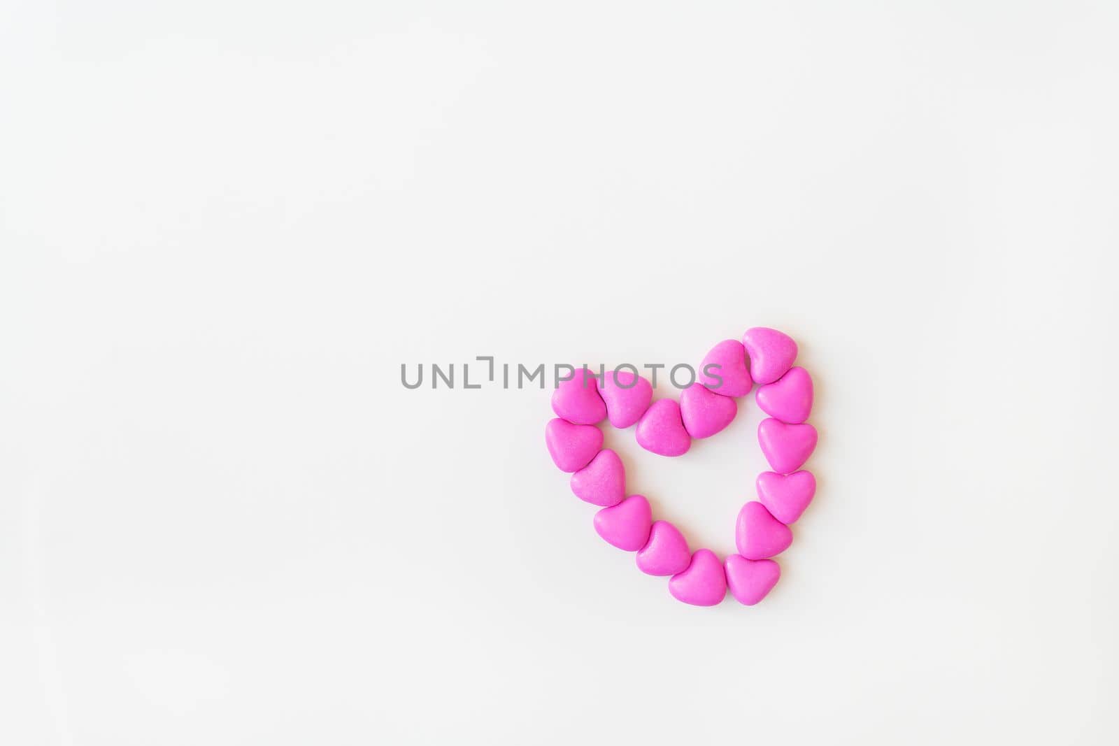 Valentine's day pattern background flat lay top view of heart shaped pink candies scattered on white background. Place for an inscription