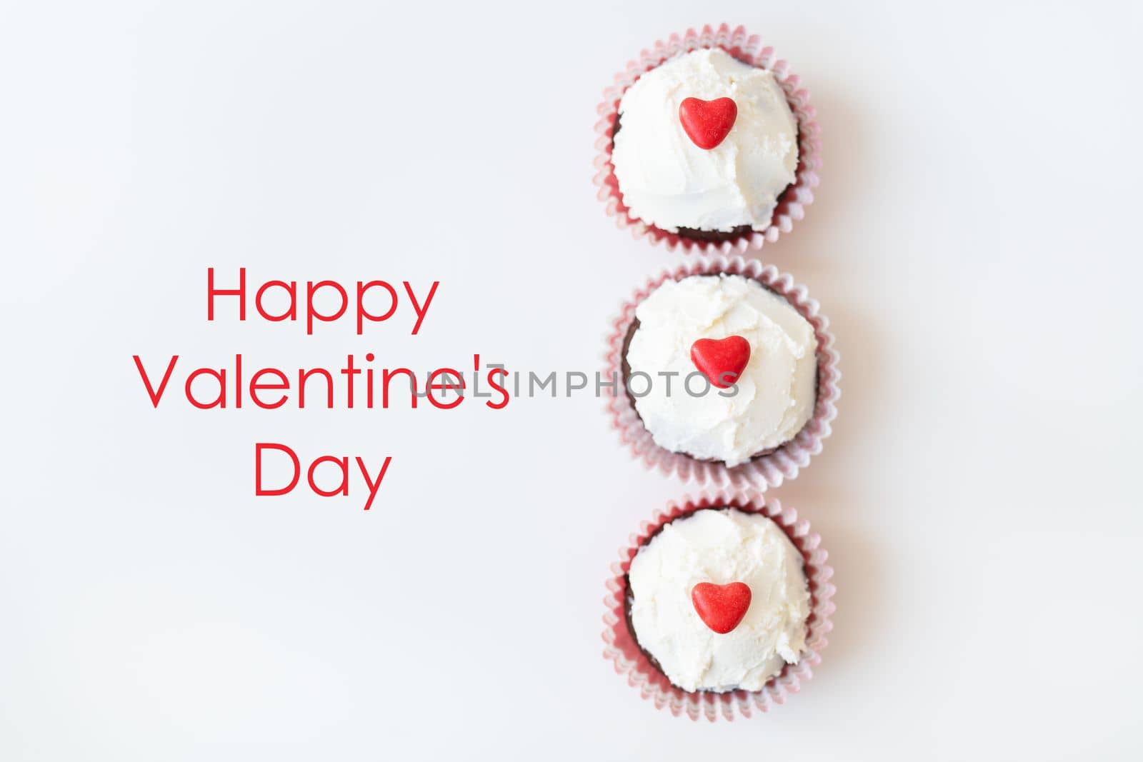 Valentine-14 February. Sweet chocolate muffins with butter cream and a red heart for decoration on a white background. Happy valentines day lettering