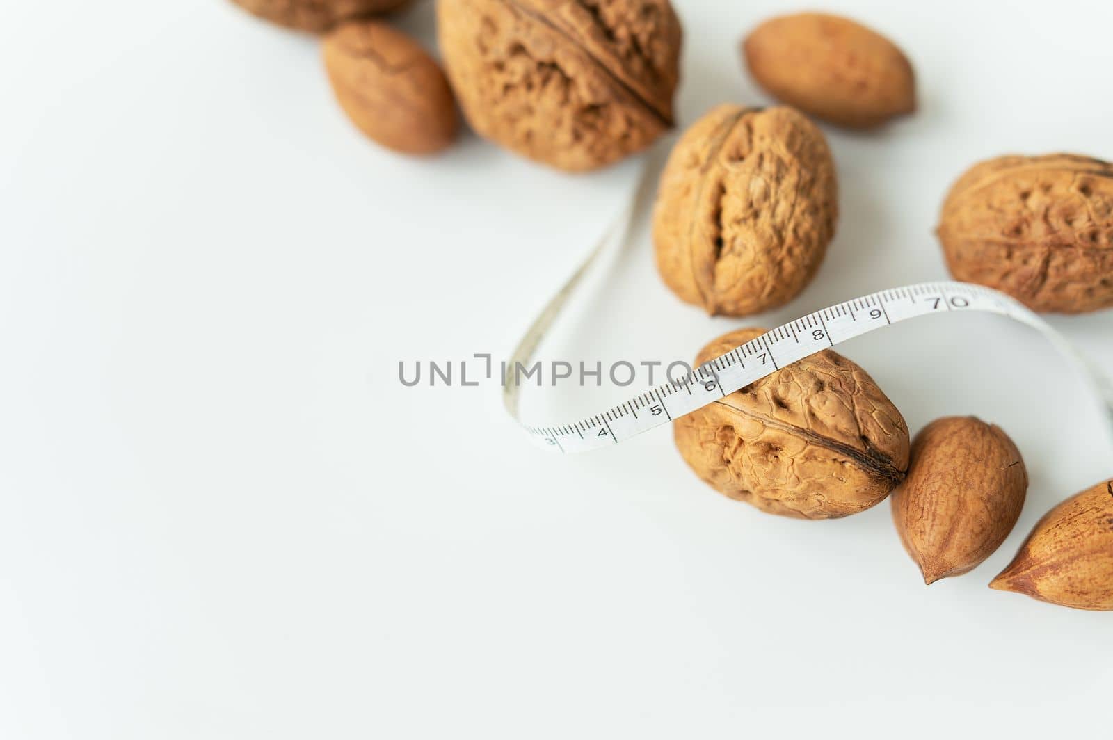 Beautiful whole walnut kernels, whole nuts in shell on a white table. Centimeter among nuts, low calorie nuts. Selective focus