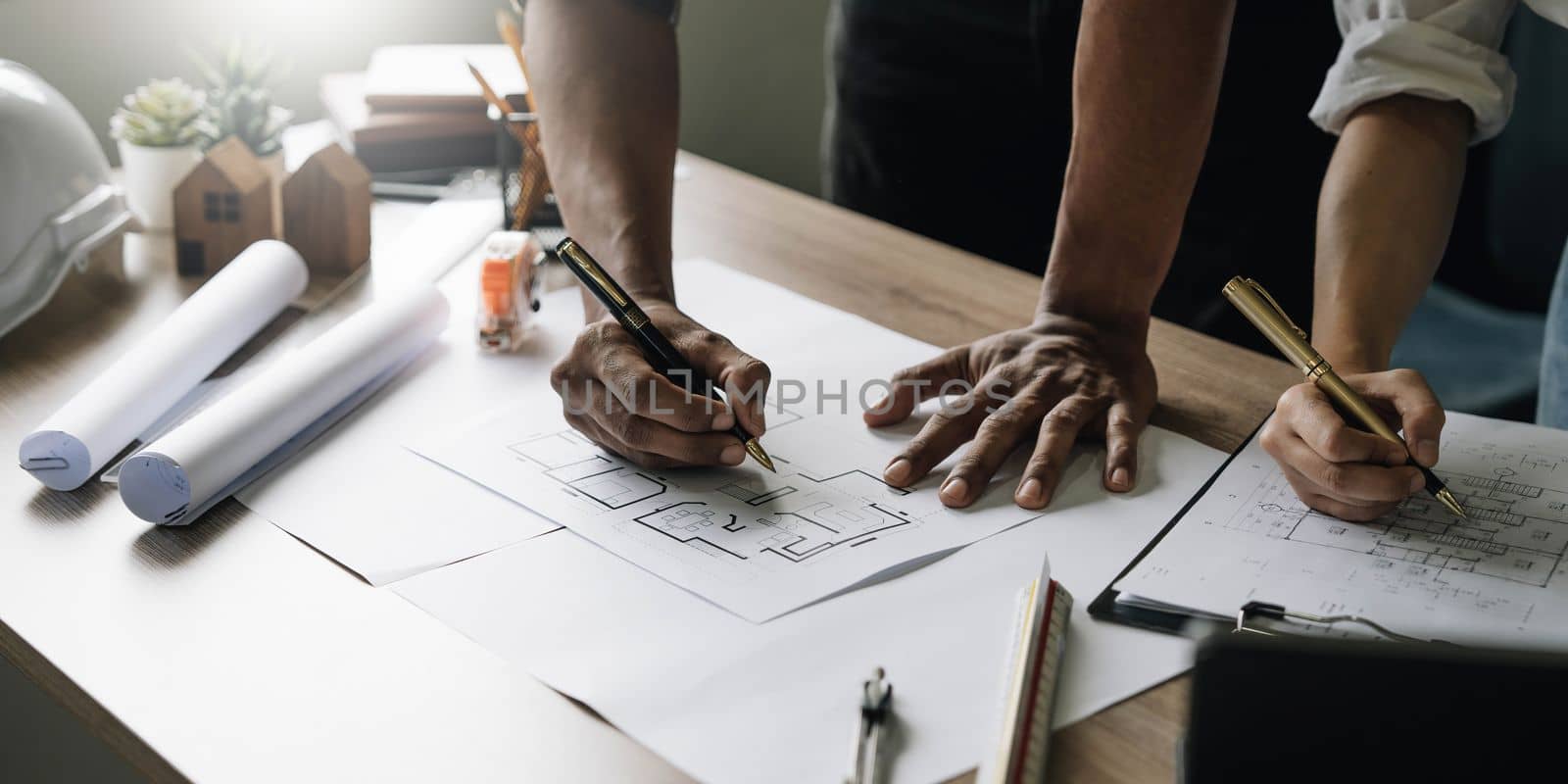 Team construction engineers working at construction site with blueprint on table.
