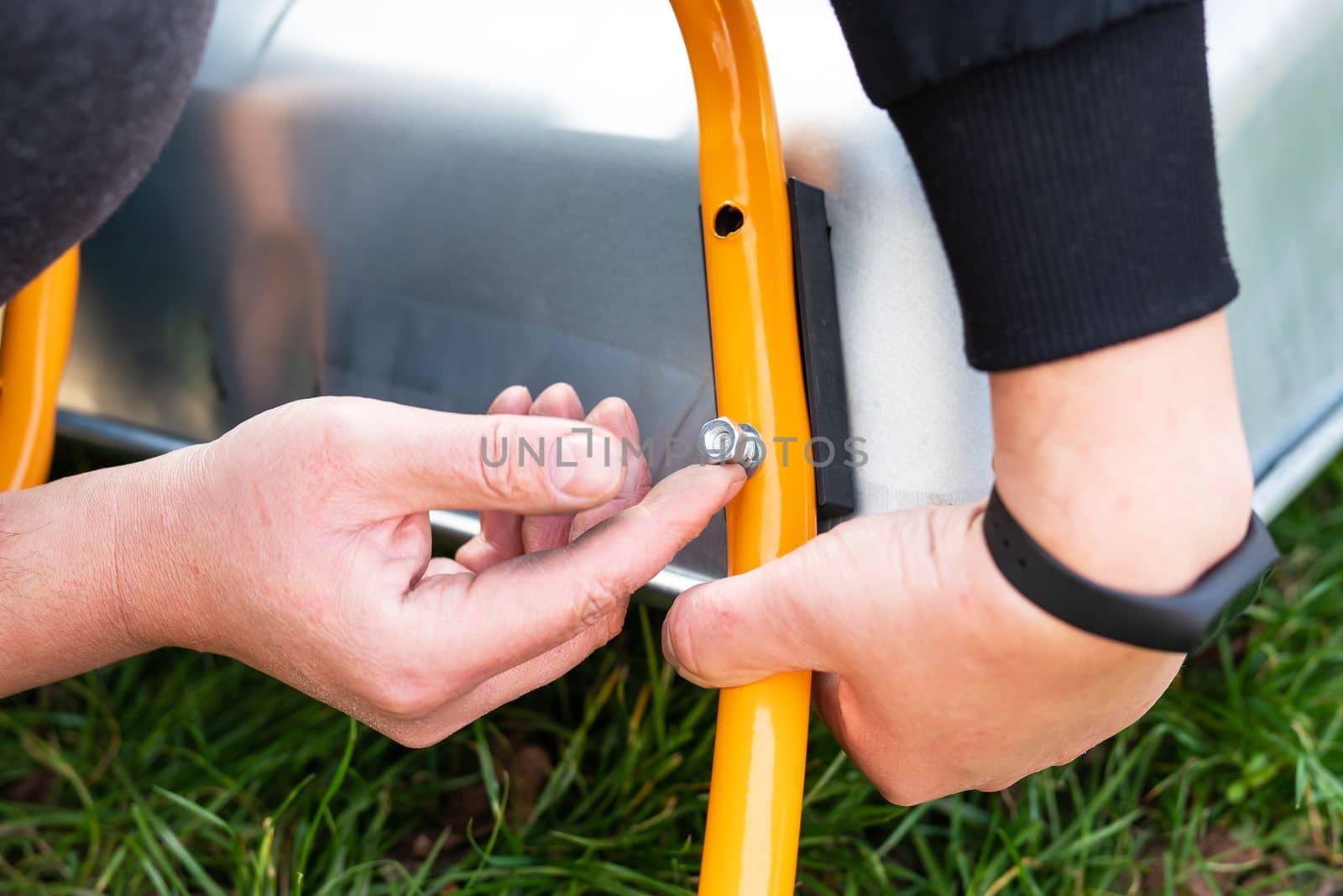 A man repairs a garden wheelbarrow, unscrews the bolts. Farm work, seasonal cleaning before autumn. On the street