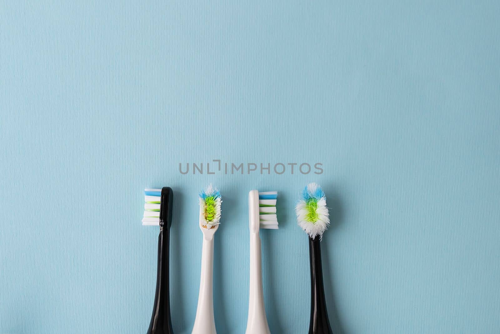 Modern electric toothbrush on a blue background, it's time to change the brush - old and new brush attachment. Hygiene concept for daily oral care. by sfinks