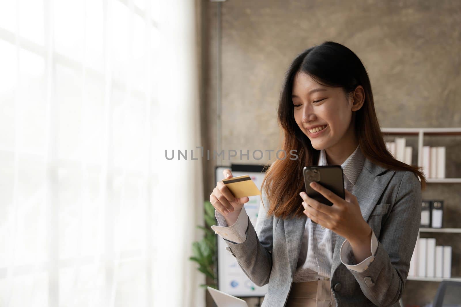 Happy asian Business woman pay online using mobile phone at the office