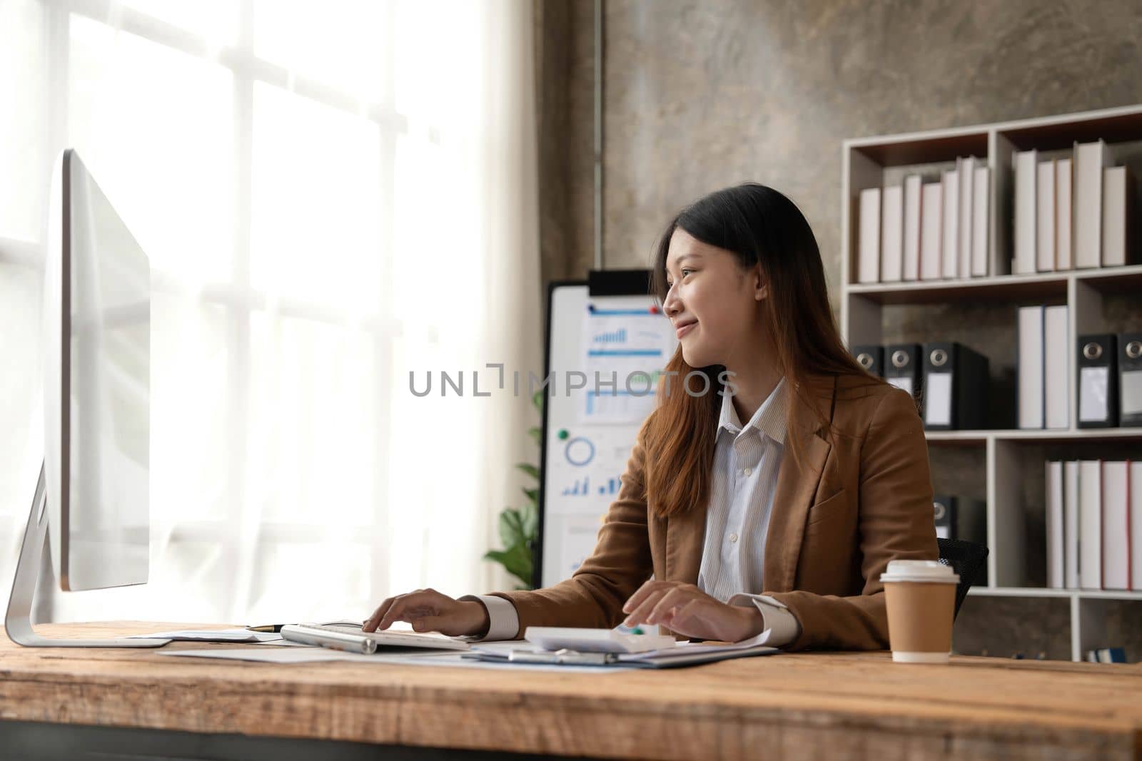 Young woman working on a laptop in the office. Asian businesswoman sitting at her workplace in the office. Beautiful Freelancer Woman working online