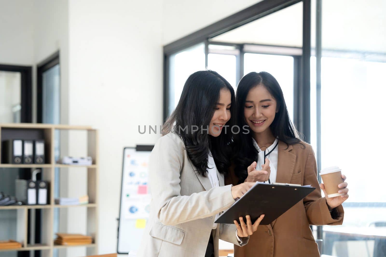 Attractive young asian woman using laptop computer while standing in a office. by wichayada