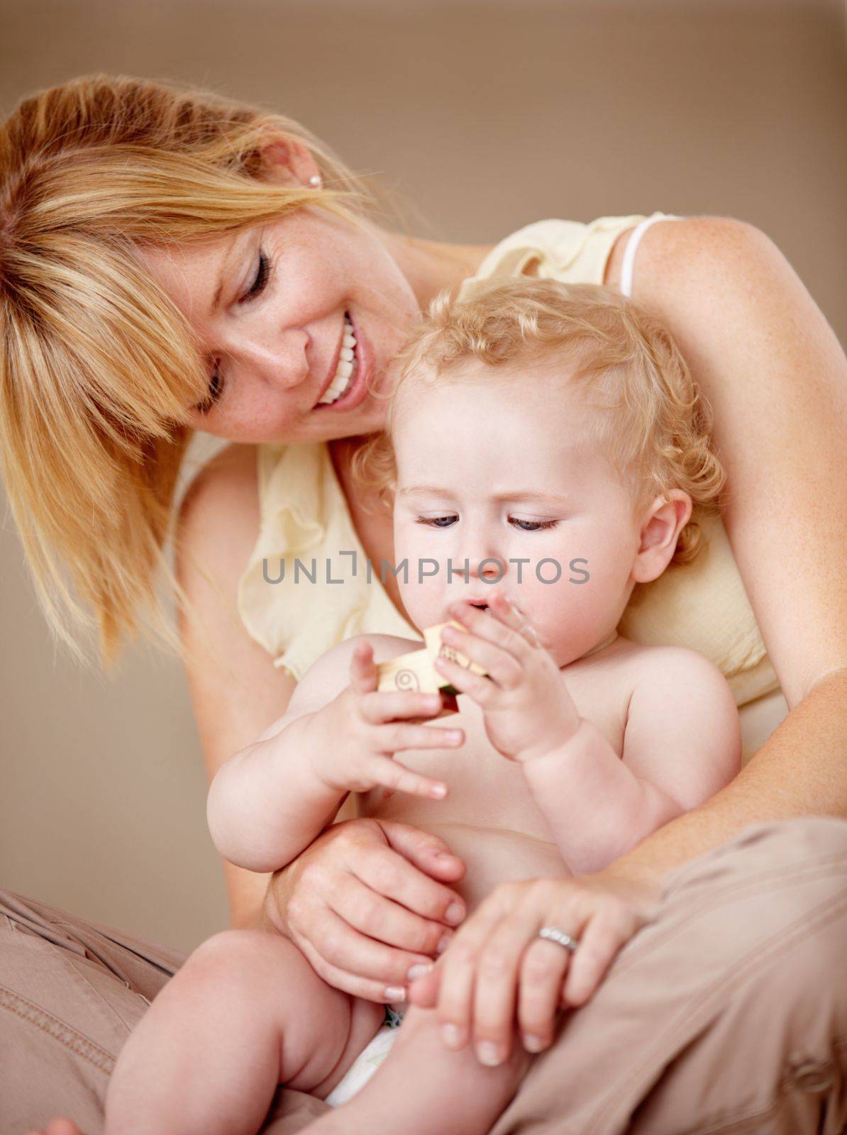 Proud of her little boy. Cute baby boy being held by his smiling mother while holding something