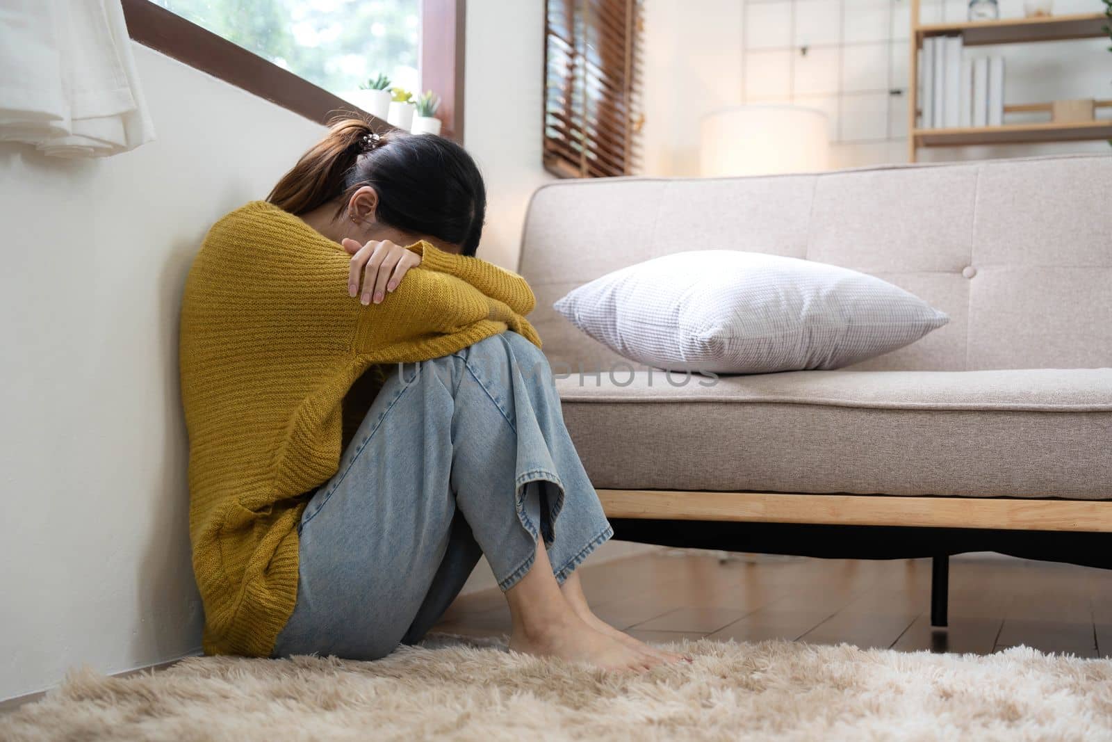 Hand on temples of young unhappy sadness Asian girl sitting on sofa. She is feeling not very good due to her sickness and having a headache. Seen from the front. Stress and sickness concept...