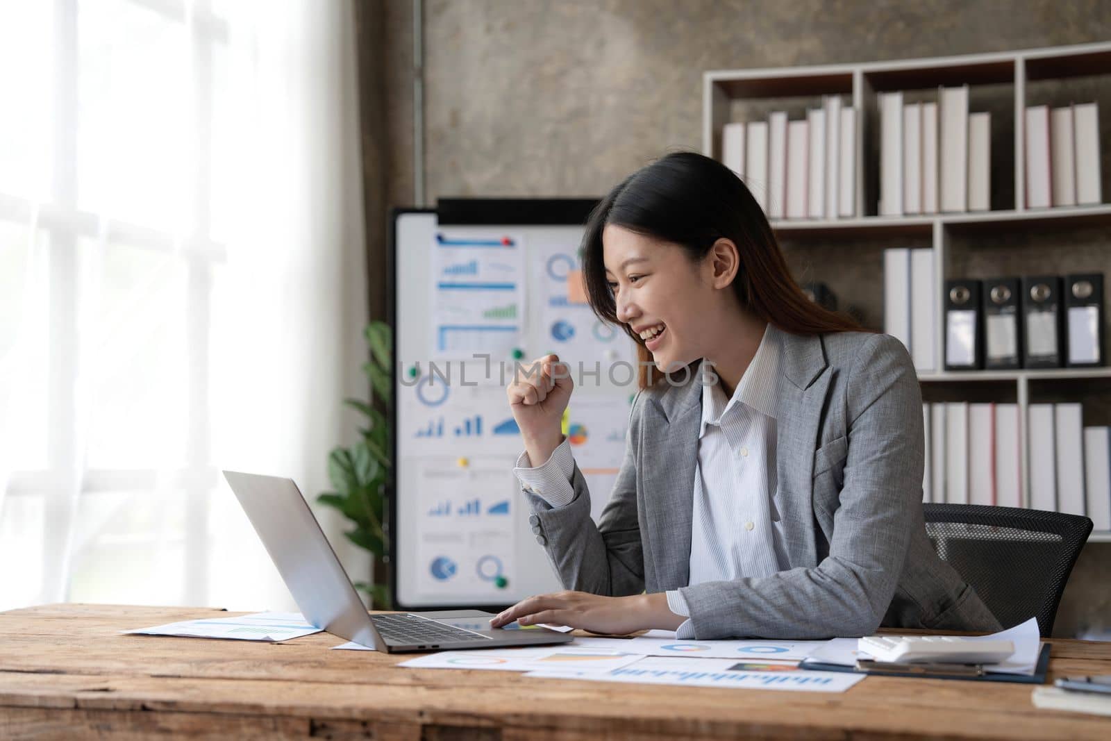 Pretty Asian businesswoman sitting on a laptop And the work came out successfully and the goal was achieved, happy and satisfied with her..