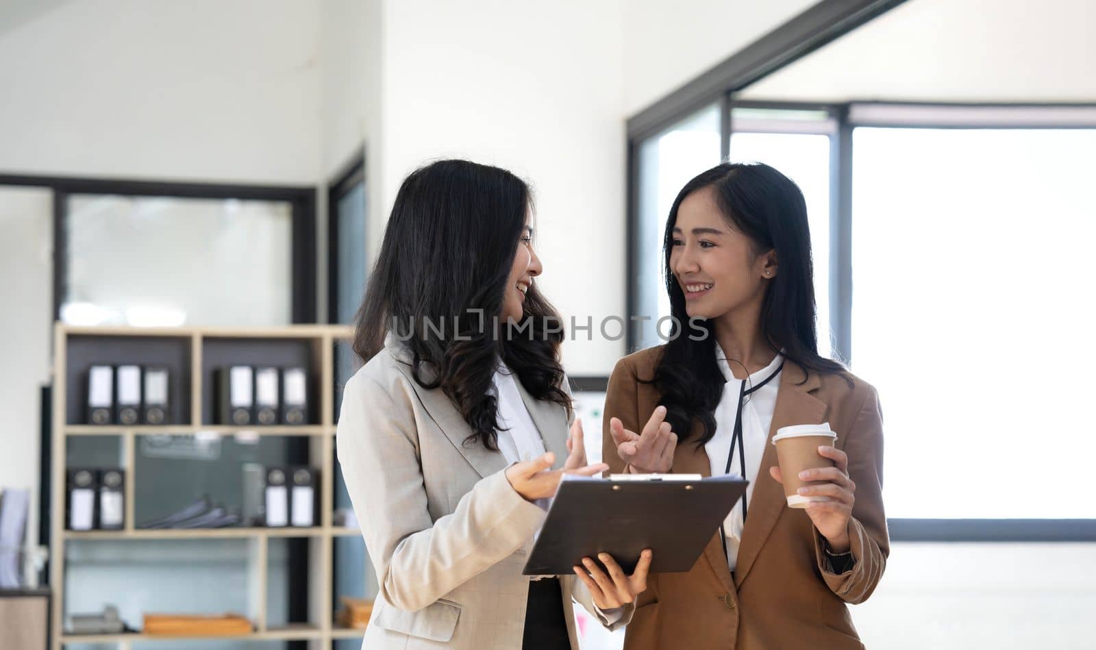 Attractive young asian woman using laptop computer while standing in a office. by wichayada