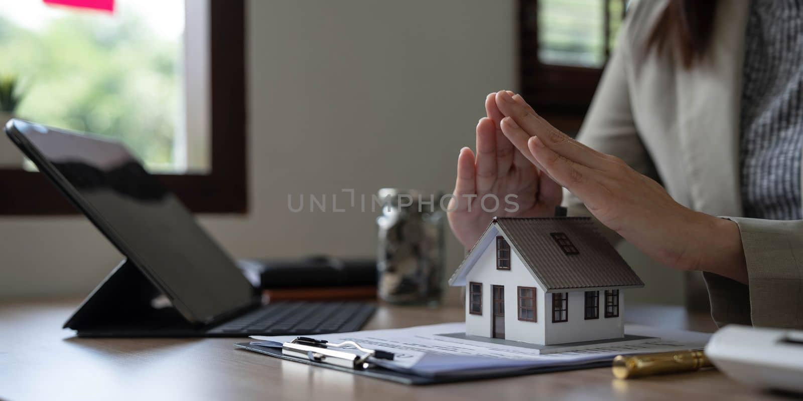 real estate agent use their hands to protect the red roofs, the concept of protecting houses using the gestures and symbols of real estate investors, taking care of credit and contracts...