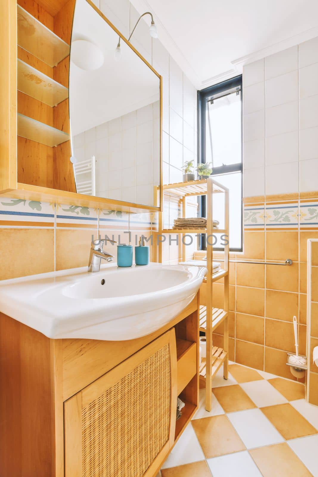 a bathroom with wooden cabinets and white tiles on the floor, in front of a large mirror above the sink