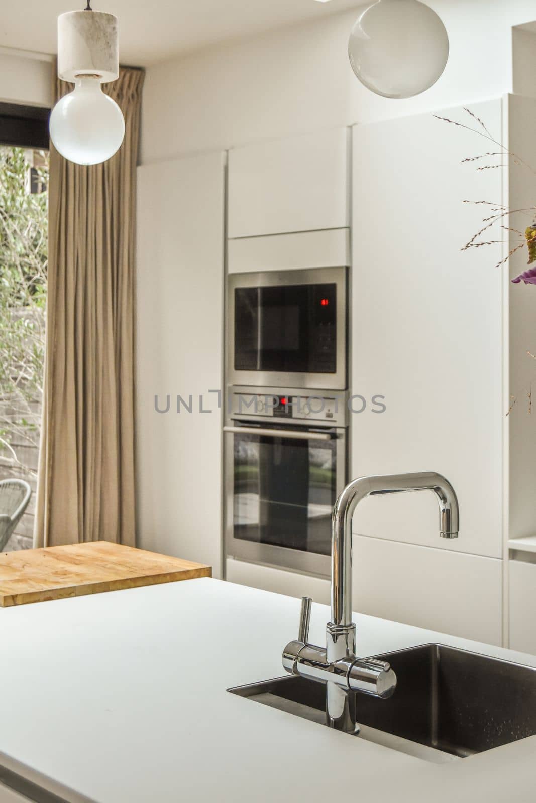 a kitchen with an oven, sink and window in the back ground looking out to the trees outside on the other side