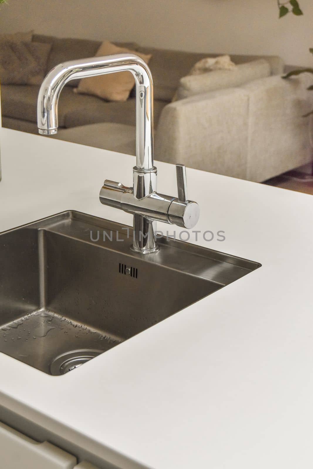 a kitchen sink with water running from the fauced tap in it's right hand held over the sink