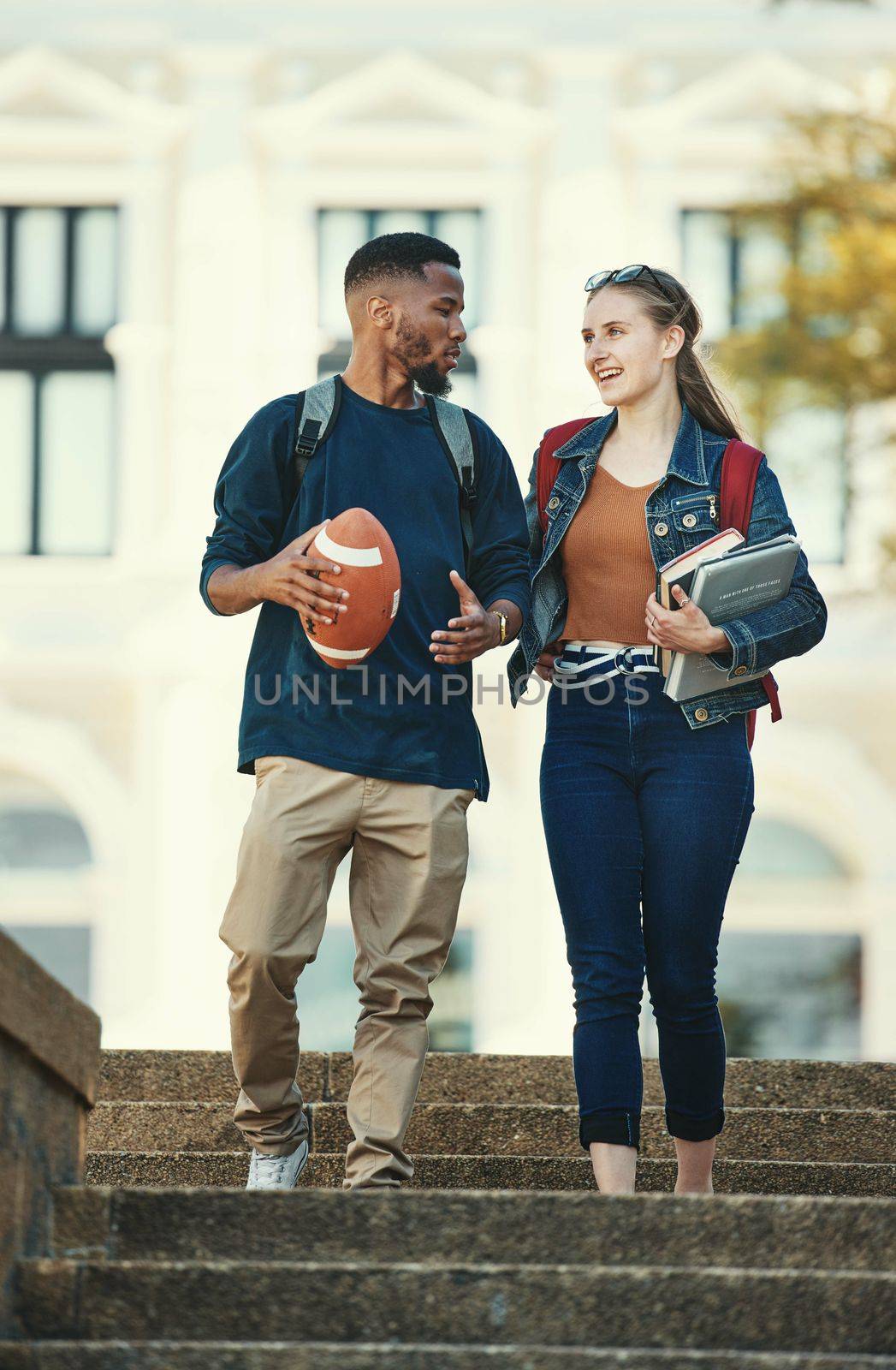 Black man, woman or university students walking and talking on college, school or education learning campus. Smile, happy or interracial couple or bonding friends on steps and football or study books.