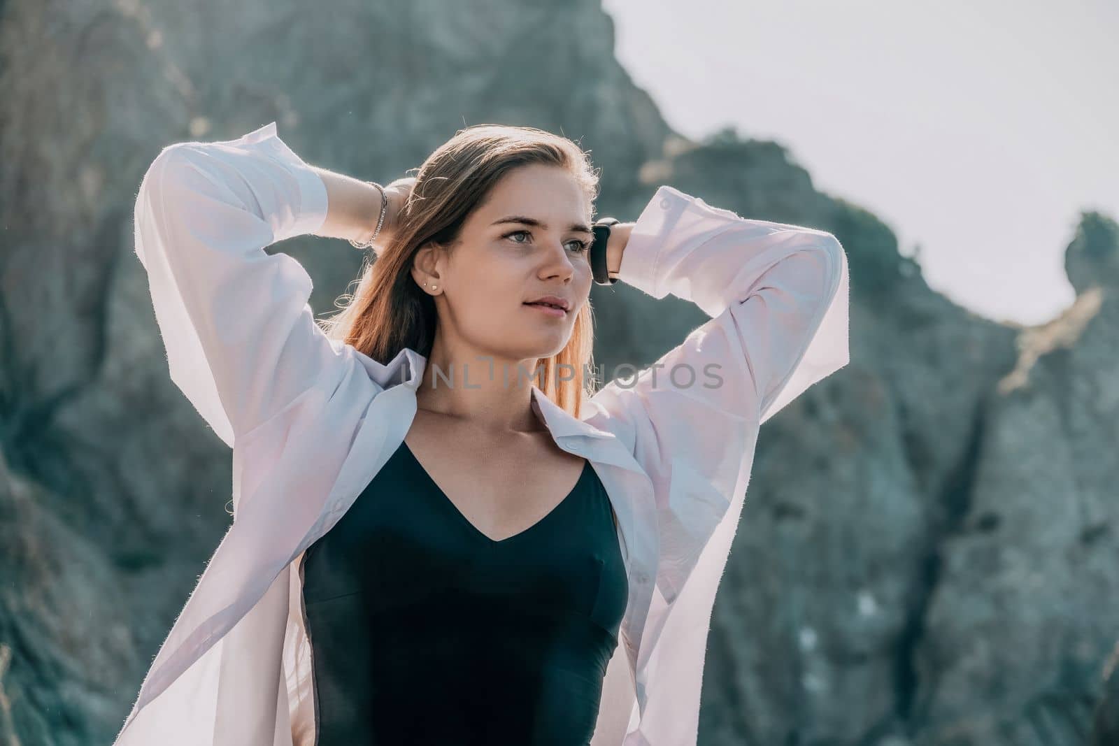 Young woman in black bikini and white shirt on Beach. Girl lying on pebble beach and enjoying sun. Happy lady in bathing suit chilling and sunbathing by turquoise sea ocean on hot summer day. Close up by panophotograph