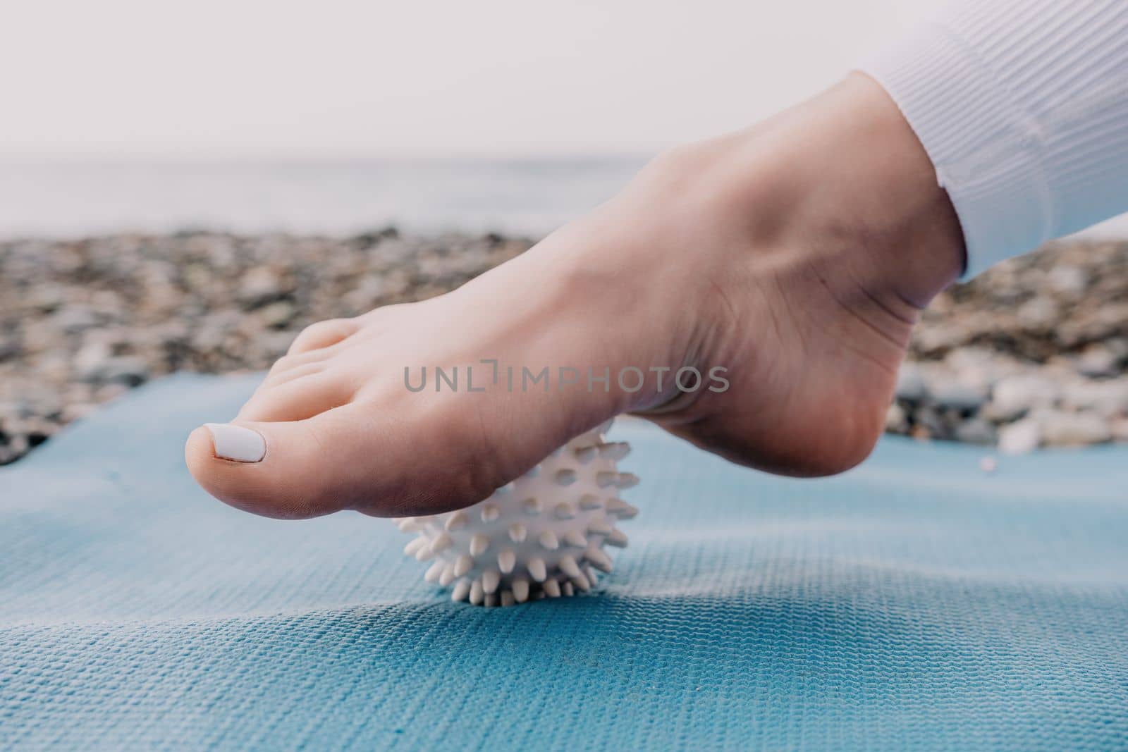 Woman yoga sea. Well looking middle aged woman with braids dreadlocks in white leggings and tops doing stretching pilates on yoga mat near sea. Female fitness yoga routine concept. Healthy lifestyle