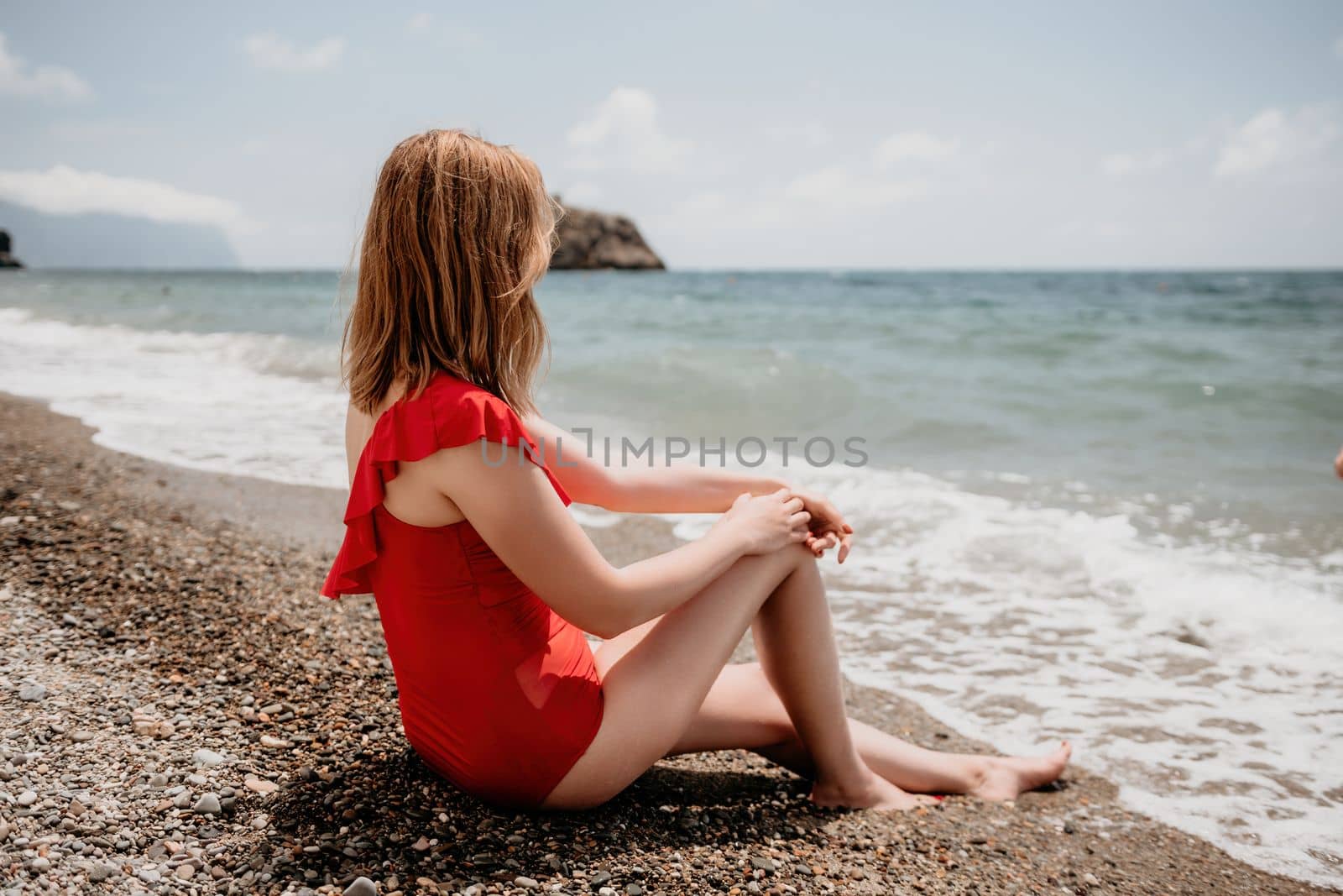 Young woman in red bikini on Beach. Blonde in sunglasses on pebble beach enjoying sun. Happy lady in one piece red swimsuit relaxing and sunbathing by turquoise sea ocean on hot summer day. Close up,