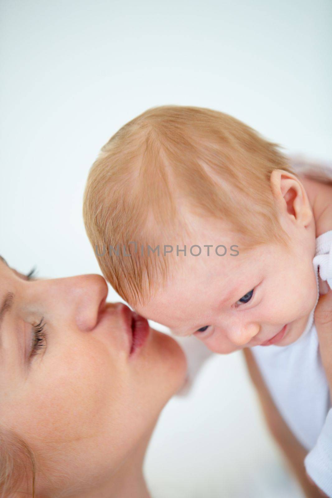 Babies have that special scent...Closeup shot of a mother tenderly kissing her newborn babys head. by YuriArcurs