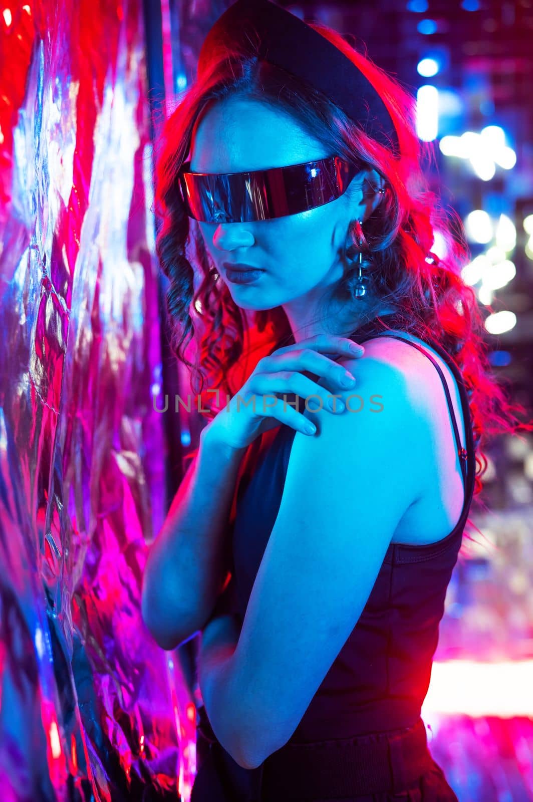 Close-up portrait of caucasian woman in sunglasses in neon light against foil wall. by mrwed54